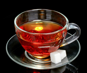 black tea, mint and sugar in cup on black background