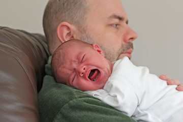 Crying newborn baby on father's shoulder