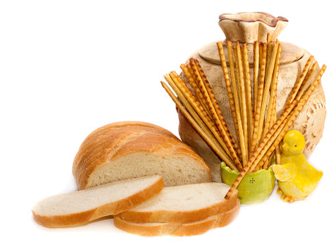 Jug, bread and grain straws on a white background