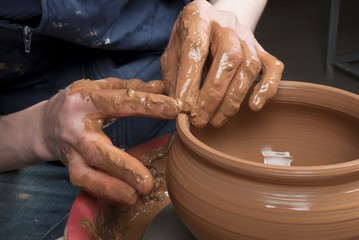 hands of a potter, creating an earthen jar on the circle