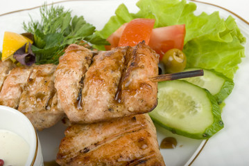 pork (or chicken) on a grill spit with salad