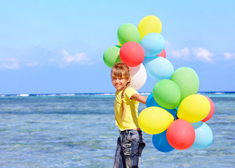 Child playing with balloons at the beach