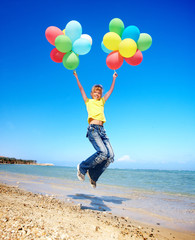 Child playing with balloons at the beach