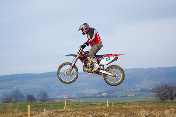 Fototapeta na wymiar Motokross motocyklista lecący w powietrzu skaczący nad ziemią