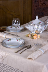 Piękne porcelanowe nakrycie stołu w restauracji przykrytego koronkowym obrusem