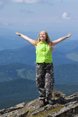 happy woman standing at mountain peak