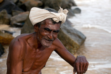 Fototapeta na wymiar Starzec ze Sri Lanki siedzi na brzegu oceanu