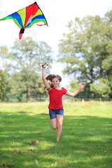 girl running with a colorful kite outdoor smiling