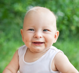 Portrait of smiling happy baby boy on natural background in summ