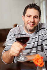 Mann prostet mit Glas Rotwein