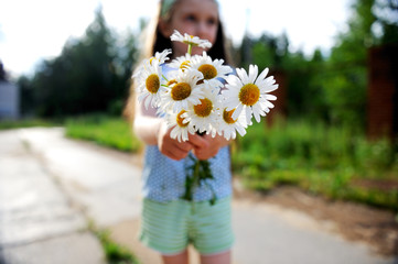 Outdoors portrait of adorable child girl showing daisies