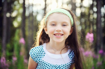 Outdoors portrait of adorable smiling blue-eyed child girl