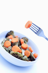 Brocoli con zanahoria en plato sobre fondo blanco