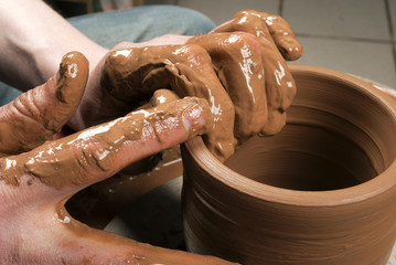 hands of a potter, creating an earthen jar on the circle
