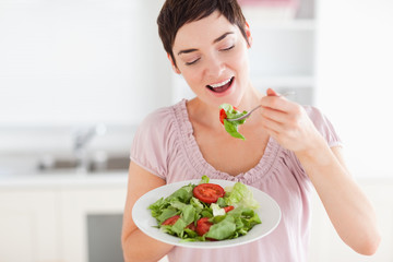 Obraz na płótnie Canvas Smiling woman eating salad