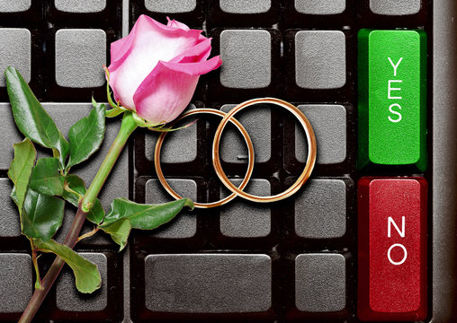 Wedding Rings And Red Roses On Computer Keyboard