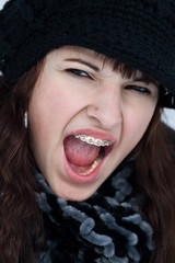 Junge schreiende Frau mit Zahnspange M&uuml;tze und Schal