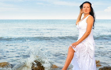 Fototapeta na wymiar The woman in a white sundress on seacoast.