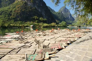 Gordijnen Bamboo raft with hill and river © cityanimal