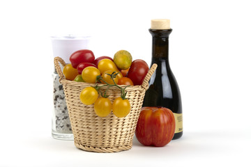 Korb mit Biotomaten, Pfeffermühle und Balsamiko
