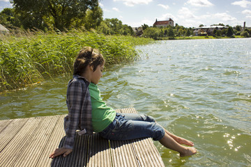 boy relaxing at riverside, Trakai, Lithuania