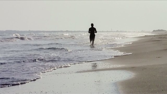 jogging sulla spiaggia in controluce