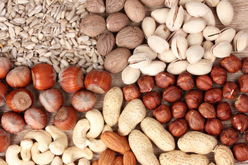 nutmeg, peanuts, hazelnuts and almonds on wooden background