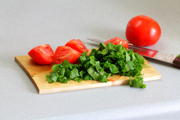 Sliced tomatoes, a parsley, a wooden board and a knife