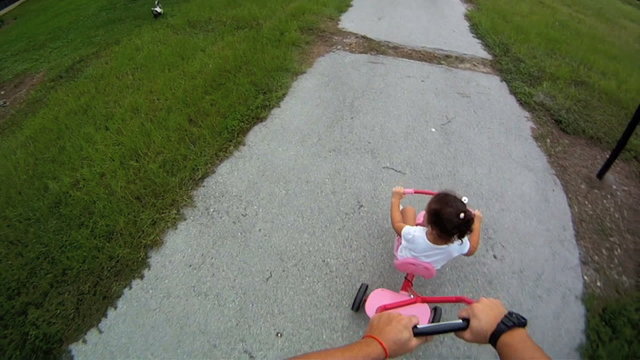 Father walking child on tricycle in the park