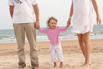Family parents and baby walking on the beach