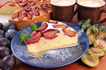 Plum pie, coffee and plums on a wooden background