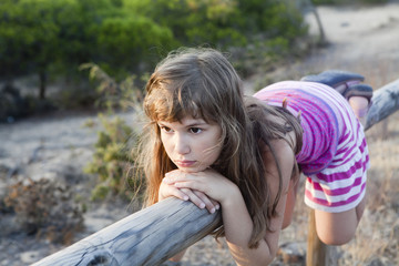 girl with leaning on wood fence with faraway look