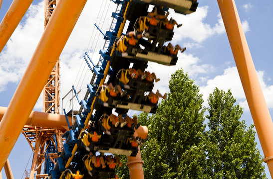 Roller Coaster View Against Summer Sky With Passengers