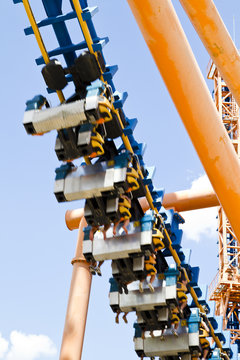 roller coaster view against summer sky with passengers hanging f