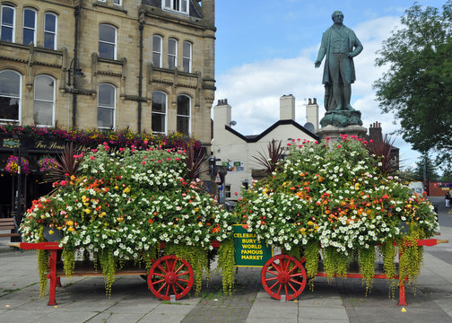 A statue and a pretty floral display on barrows in the Lancashire market town of Bury Greater Manchester U.K..