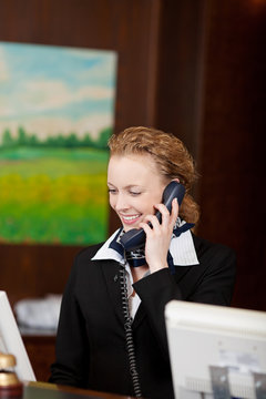 lächelnde mitarbeiterin im hotel telefoniert