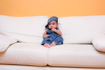 neonato con tuta in jeans sul divano