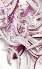 Sliced Red Onion rings on whte chopping board.