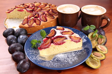 Plum pie, coffee and plums on a wooden background