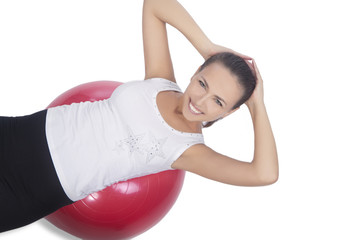 Fototapeta premium happy and smiling brunette girl with red fitball isolated on whi