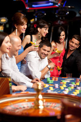 happy caucasian friends playing roulette in casino - 34834930