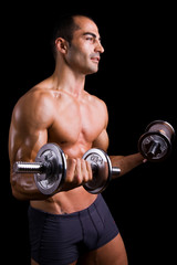 Fototapeta na wymiar Muscular young man lifting dumbbells on black background.