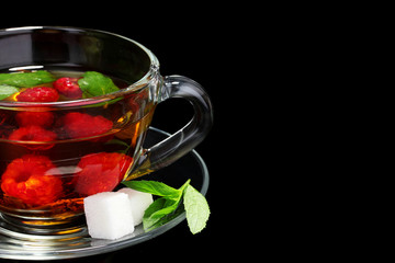 black tea, raspberry, lime and mint in cup on black background