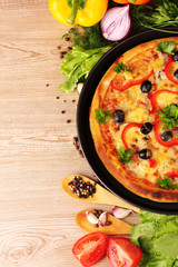 tasty pizza on the plate and vegetables on a wooden background