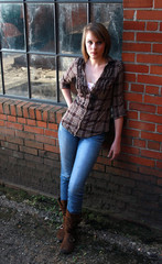 A young woman standing by a brick wall