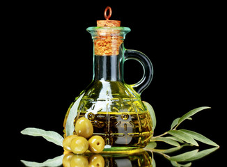 olive oil in jar and olives on black background