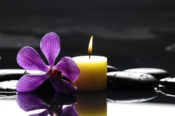 Foto op Plexiglas brandende spa-kaarsen met roze orchidee en stenen reflectie © Mee Ting