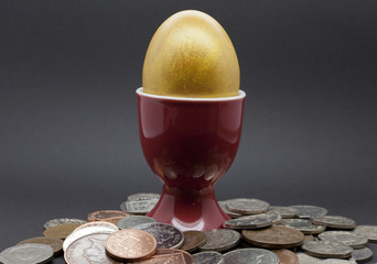 Egg in a red eggcup with Engish coins on a black background