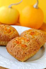 Pumpkin muffins with a pair of pumpkins at the background.