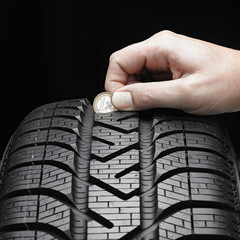 Checking the tread pattern of a winter tire with euro coin